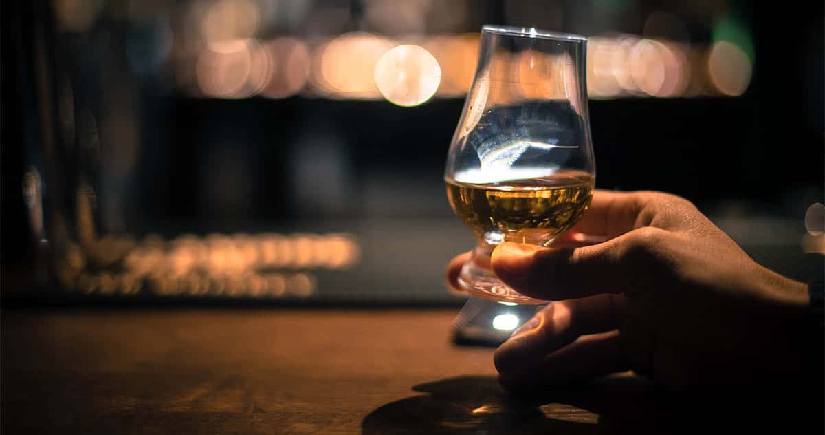 Hand holding a Glencairn single malt whisky glass - bizoo_n (AdobeStock 247316064)