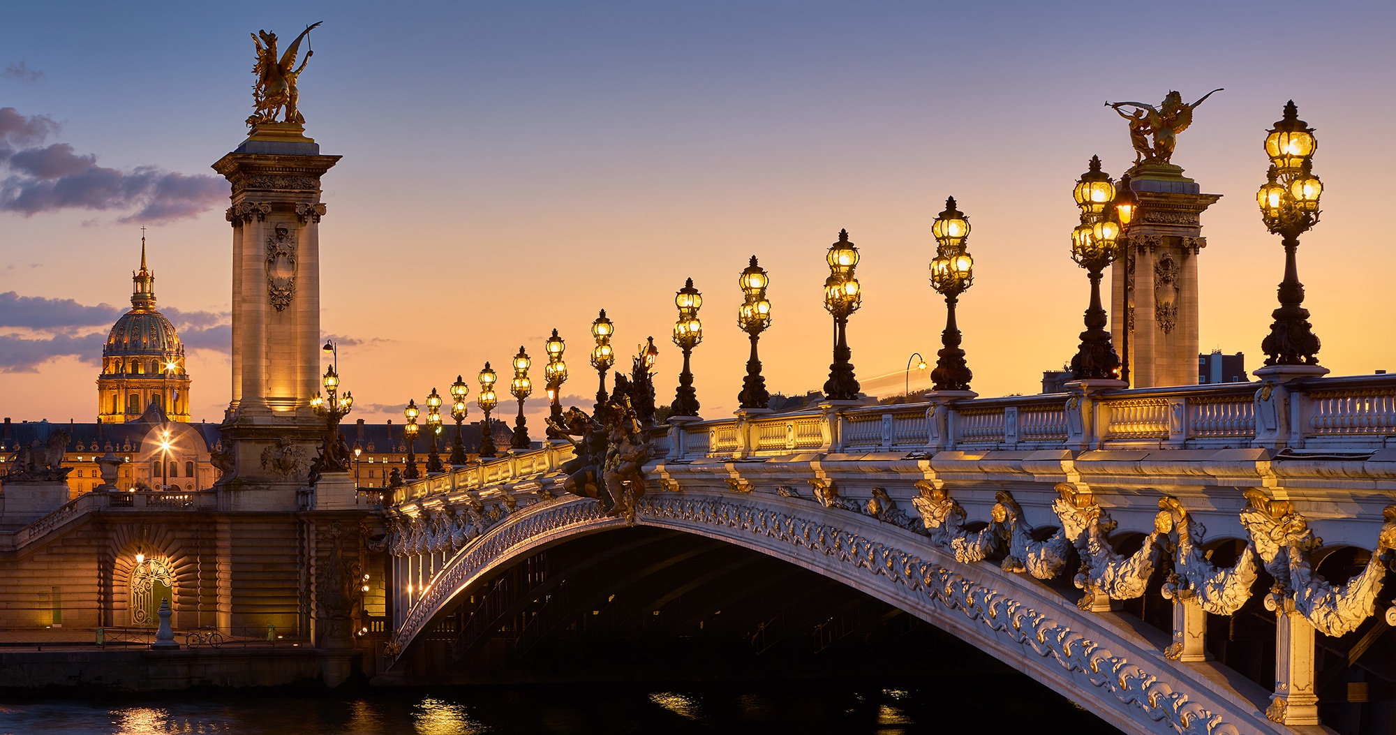 Pont Alexandre III Bridge and illuminated lamp posts at sunset w